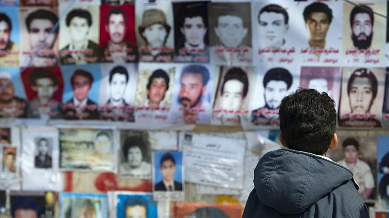 ليبي ينظر إلى صور بعض ضحايا مذبحة سجن أبو سليم.