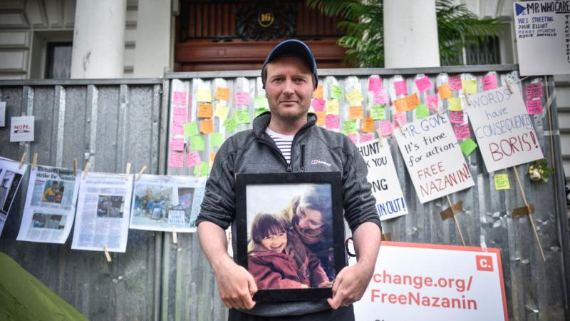 زوج راتكليف يحمل صورة لها ولابنتها أمام منزلهما في بريطانيا.