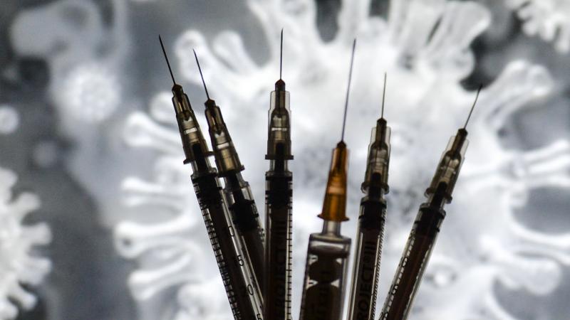  صورة تعبيرية تظهر حقن اللقاح أمام رسم عن فيروس كورونا (غيتي)