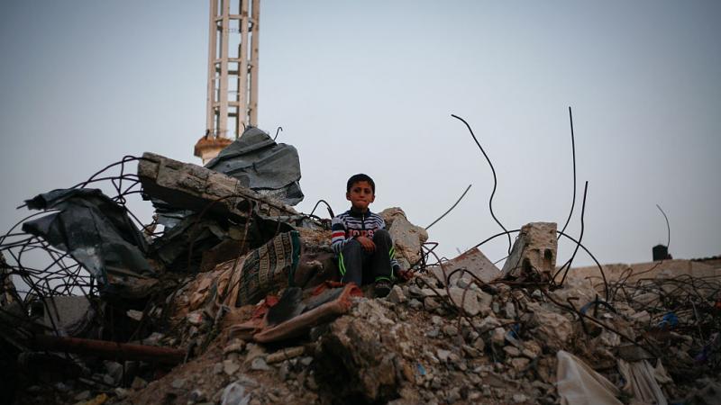 على أنقاض منزله الذي دمرته الغارات الإسرائيلية على غزة عام 2014 (غيتي)