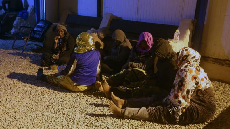 نساء مهاجرات يسترحن على الأرض في ميناء تاجوراء الليبي 