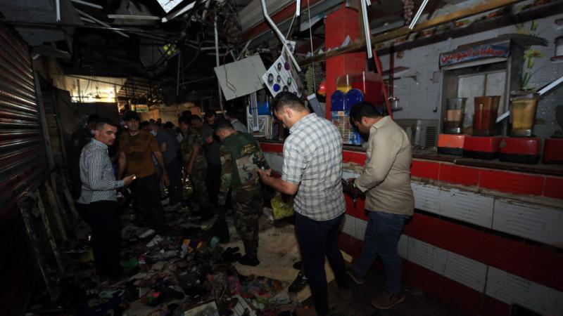قوات الأمن العراقية ومواطنون يتفقدون موقع الانفجار في منطقة الصدر ببغداد (غيتي)