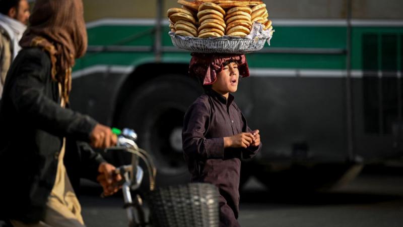 طفل يحمل الخبز على رأسه أثناء سيره في شارع بكابل (غيتي)