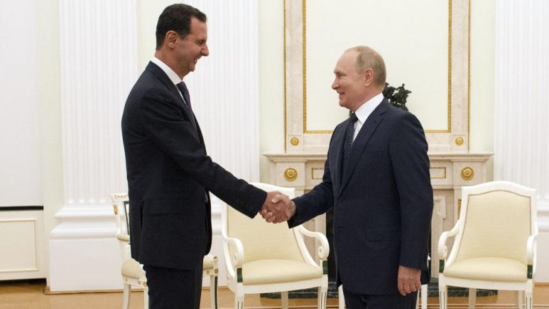 بشار الأسد مصافحًا الرئيس الروسي فلاديمير بوتين قبل ساعات من إعلان الأخير دخوله الحجر الصحي (غيتي)