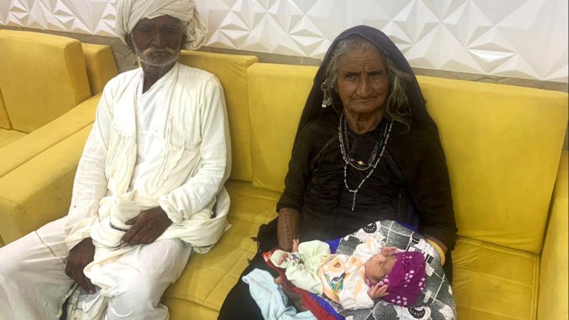 السيدة العجوز تجلس بجانب زوجها حاملةً مولودها الجديد (موقع صن)