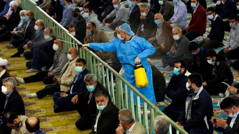 عامل إيراني في المجال الصحي يرشّ مواد مطهّرة بين المصلين