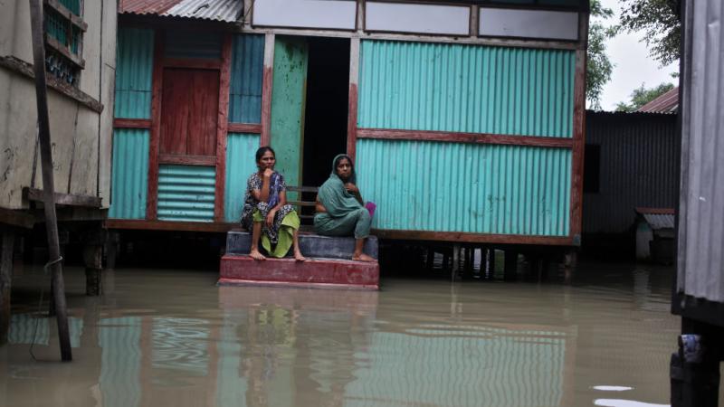 نساء يجلسن عند مدخل منزل خلال فيضانات منطقة ماوا في بنغلاديش (أرشيف – غيتي)
