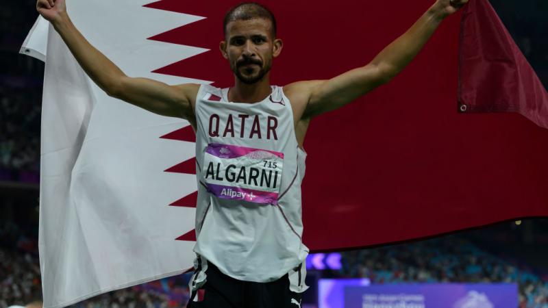 العداء الكرني رافعا علم قطر لحظة فوزه بالميدالية الذهبية