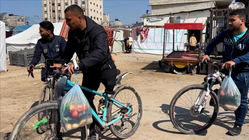 فلسطينيون مبتورو الأطراف يوزعون الخضار على دراجاتهم الهوائية للنازحين في رفح - الأناضول